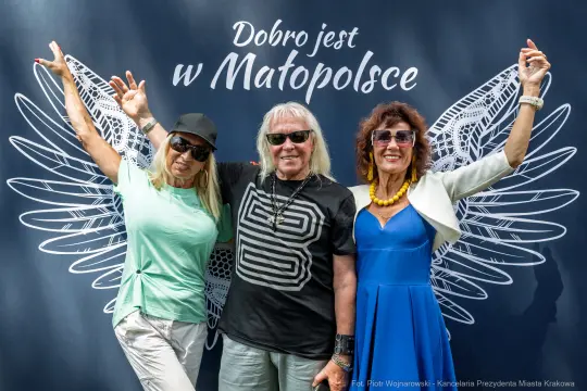 Trzy osoby pozujące z uśmiechem przed muralem z napisem "Dobro jest w Małopolsce".