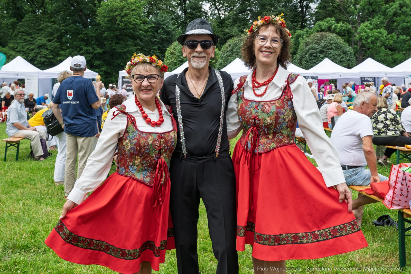 Trzy osoby w tradycyjnych strojach ludowych, w otoczeniu festiwalu.  Autor: Piotr Wojnarowski