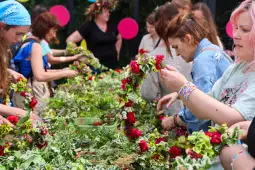 Kobiety tworzące wianki z kwiatów i zieleni podczas warsztatów florystycznych.