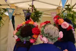 Kobiety w kwiecistych wiankach robią sobie zdjęcie.