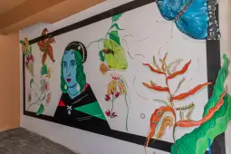 Mural z portretem kobiety w otoczeniu kolorowych motyli i roślin.