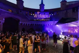 Impreza plenerowa w Krakowie z tańczącymi ludźmi i oświetleniem w tle.