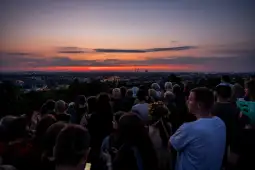 Zachód słońca nad miastem, grupa ludzi podziwiająca widok.