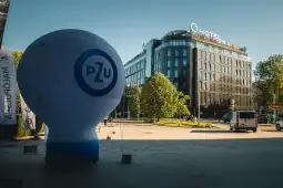 Balon reklamowy PZU przed nowoczesnym budynkiem hotelu. Zieleń w tle.