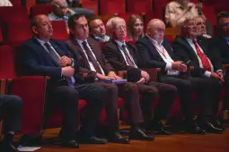 Grupa mężczyzn w garniturach siedzących na widowni w sali konferencyjnej.
