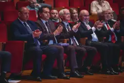 Grupa mężczyzn w garniturach klaska w trakcie wydarzenia.