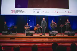 Występ muzyczny na scenie z zespołem grającym na instrumentach i wokalistą.
