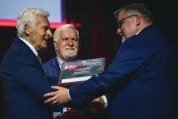 Trzej mężczyźni odbierają nagrodę podczas uroczystości.