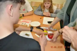 Grupa młodych ludzi uczestniczy w zajęciach, przygotowując potrawy z warzyw.