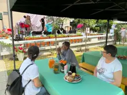 Kobiety przy stole z napojami i przekąskami, w tle przygotowania do wydarzenia na scenie.