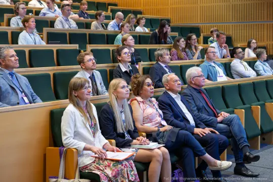 Grupa osób siedzących na wykładzie w sali konferencyjnej.