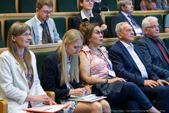 Grupa osób siedzących na konferencji, skupionych na prelekcji.