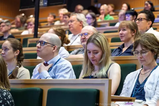 Grupa ludzi siedzących na wykładzie w sali konferencyjnej.