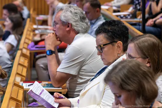 Grupa osób słuchających wykładu w sali konferencyjnej.