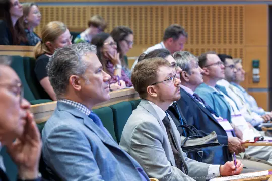Grupa ludzi słuchających wykładu na konferencji.