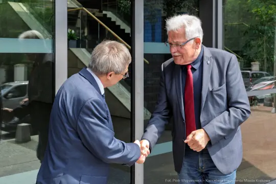Dwaj mężczyźni podają sobie ręce przy drzwiach.
