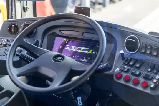 Kierownica i panel sterowania autobusu z wyświetlaczem i przyciskami.