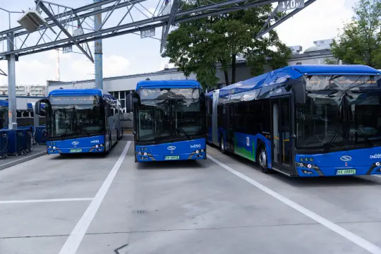 Trzy niebieskie autobusy elektryczne stojące w zajezdni.