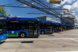 Zespół niebieskich autobusów stojących w zajezdni.