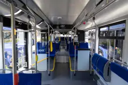 Pusty autobus miejski z niebieskimi siedzeniami.