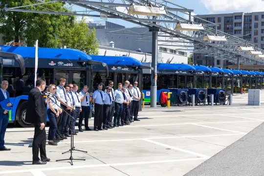 Ceremonia z udziałem pracowników transportu publicznego przy nowoczesnych autobusach.