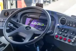 Kierownica i panel sterowania autobusu z wyświetlaczem i przyciskami.
