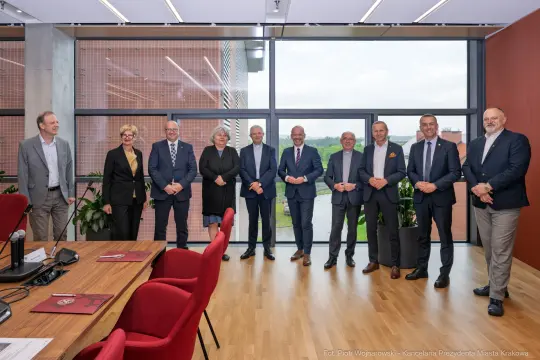 Grupa osób w formalnych strojach w nowoczesnym biurze.