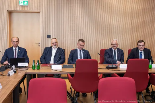 Pięciu mężczyzn siedzących przy stole w sali konferencyjnej.