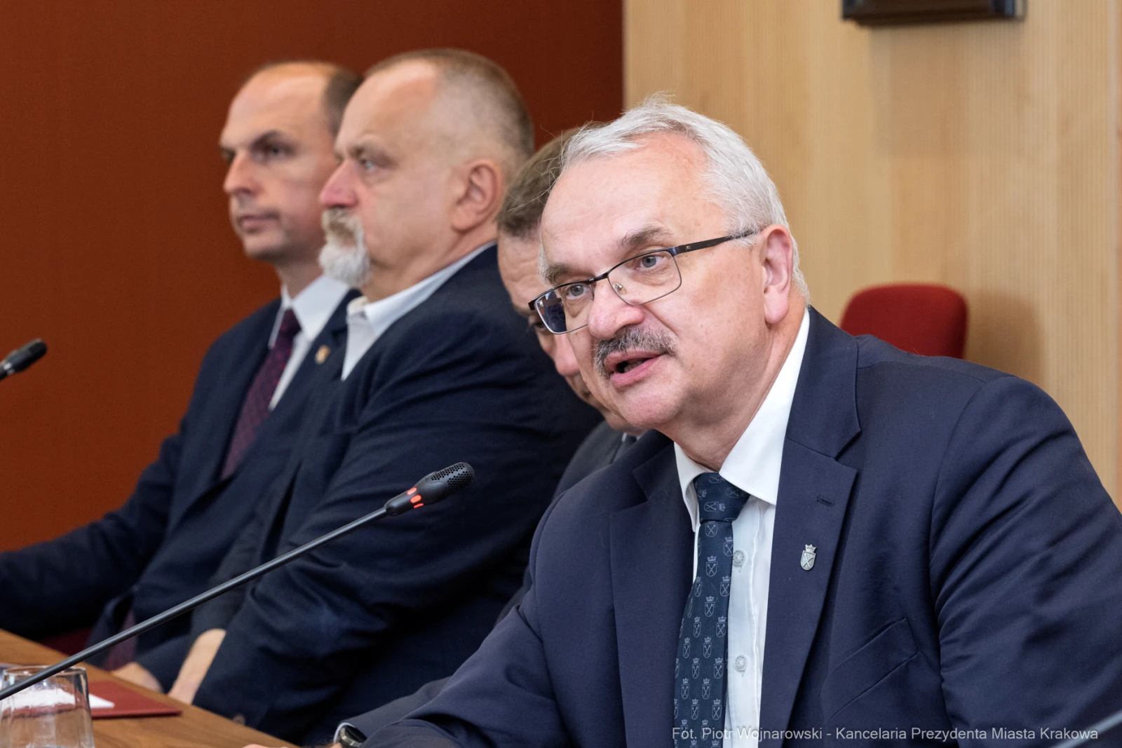 Mężczyzna w okularach przemawia podczas spotkania, obok siedzą inni mężczyźni.  Autor: Piotr Wojnarowski