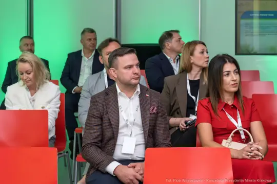 Grupa osób siedzących na konferencji, skupionych na prelekcji.