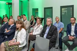 Grupa osób siedzących na sali konferencyjnej, zwróconych w stronę prelegenta.