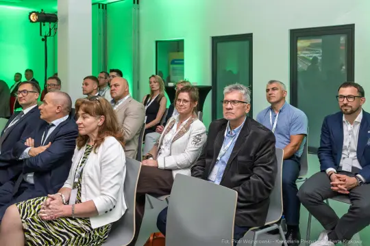 Grupa osób siedzących na sali konferencyjnej, zwróconych w stronę prelegenta.