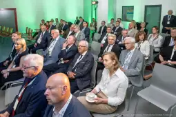 Grupa osób siedzących na konferencji, w tle zielone oświetlenie.