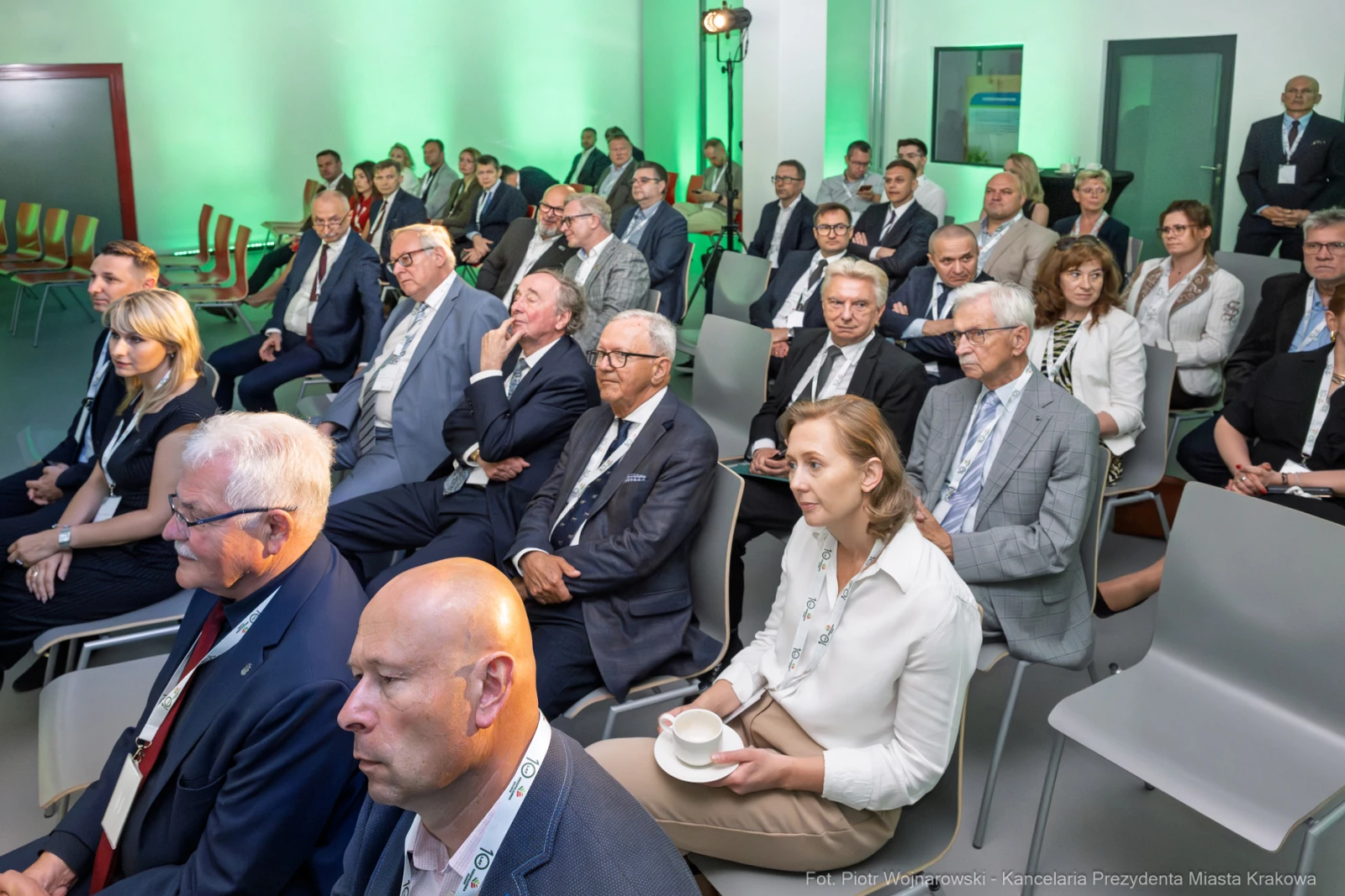 Grupa osób siedzących na konferencji, w tle zielone oświetlenie.  Autor: Piotr Wojnarowski