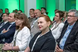 Grupa ludzi na konferencji, słuchających prelegenta.