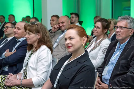 Grupa ludzi na konferencji, słuchających prelegenta.