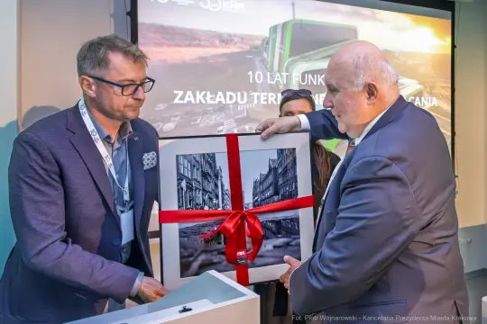 Mężczyźni wręczają sobie prezent z okazji 10-lecia Zakładu Terenu i Gospodarki.