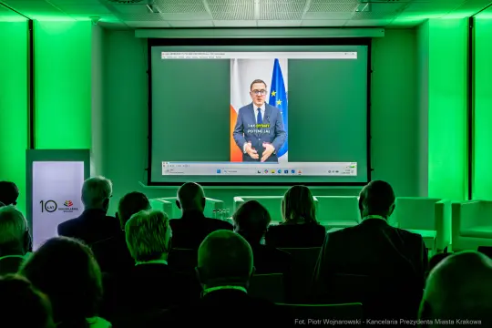 Prezentacja wideo z mężczyzną w garniturze, widoczna flaga Polski i Unii Europejskiej.