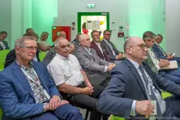Grupa mężczyzn w garniturach siedzących na konferencji.