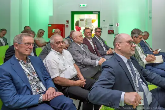 Grupa mężczyzn w garniturach siedzących na konferencji.