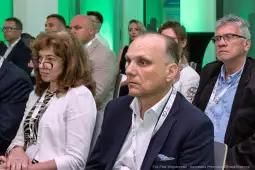 Grupa ludzi na konferencji, skupionych na prelekcji.