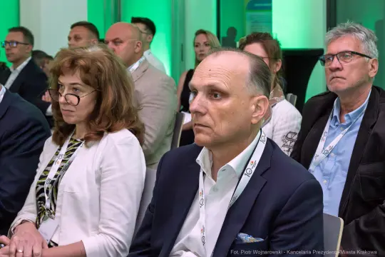 Grupa ludzi na konferencji, skupionych na prelekcji.