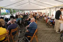 Grupa osób na wózkach inwalidzkich w namiocie, uczestniczących w wydarzeniu.