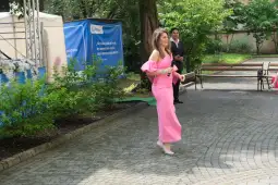 Kobieta w różowej sukni idzie po ścieżce w parku.