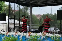 Dwie tancerki w czerwono-czarnych strojach tańczą na scenie.