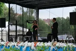 Występ artystki na scenie z towarzyszącym muzykiem i instrumentami.