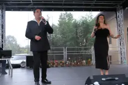 Dwójka wykonawców śpiewających na scenie podczas występu na świeżym powietrzu.