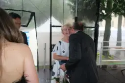 Kobieta w białej sukience w kropki rozmawia z mężczyzną w garniturze.