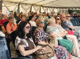 Grupa osób siedzących na widowni podczas wydarzenia na świeżym powietrzu.