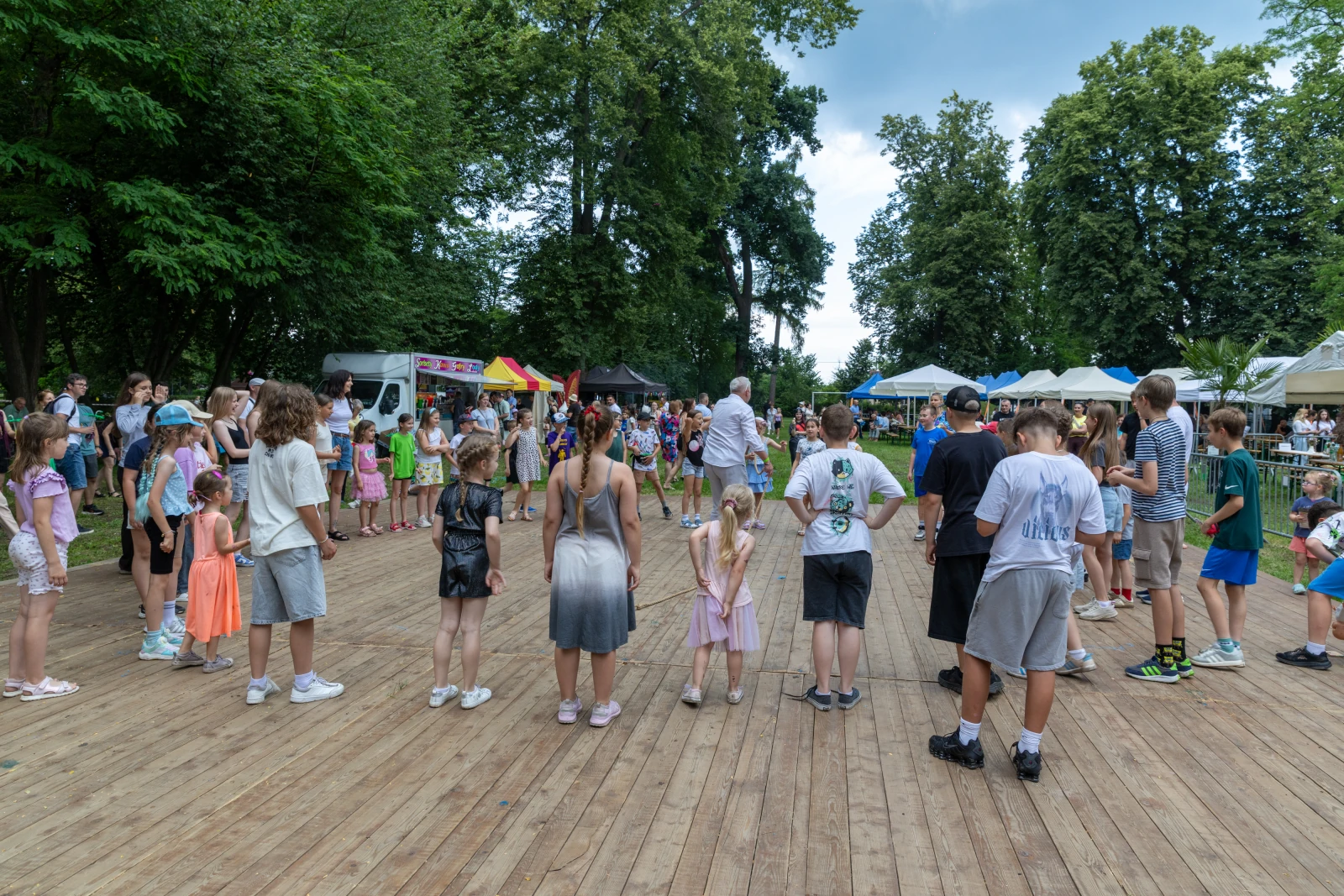 Dzieci bawią się na drewnianej scenie podczas festiwalu w parku.  Autor: Bogusław Świerzowski